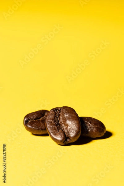 Fototapeta Three coffee beans close up isolated on a yellow surface background