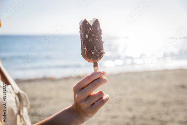 Obraz Close up of a stick of ice cream held by a girl on a beach
