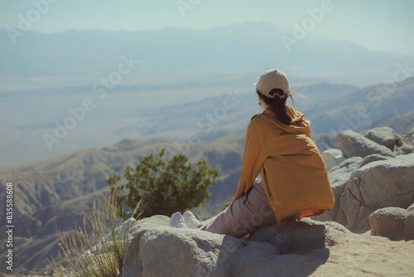 Fototapeta Travel, The woman is sitting at the top of the mountain looking at the beautiful panoramic view.