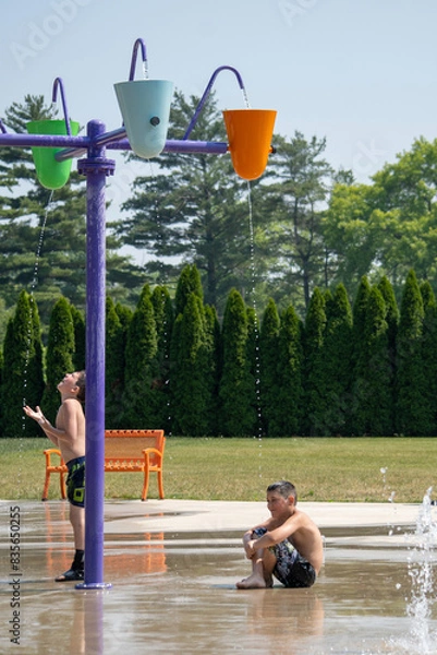 Obraz brothers in the splash pad wait for the buckets to fill and dump on them