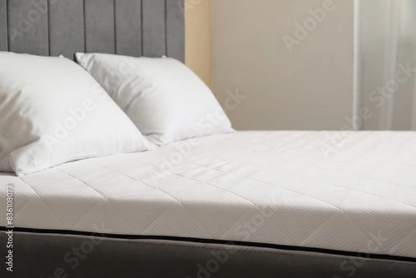 Obraz New orthopedic mattress with pillows on stylish bed in room, closeup