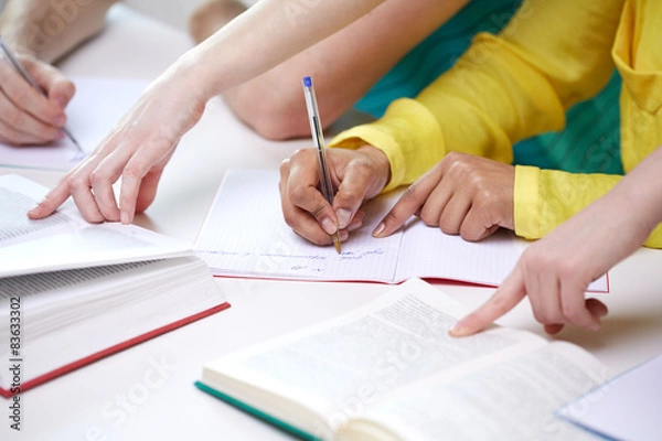 Fototapeta close up of students hands writing to notebooks
