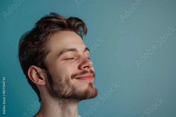 Fototapeta A close up of a man with beard and closed eyes looking to a side