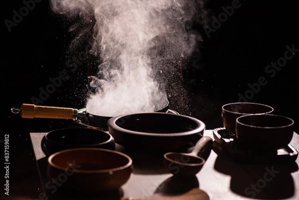 Fototapeta The cook was using a spatula to fry food in a pan of hot oil. There was a lot of smoke rising from the pan. There are wooden cups and plates placed on the table in a retro style.