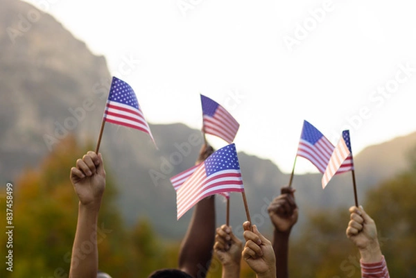 Obraz Diverse friends raising hands with flags of usa in garden