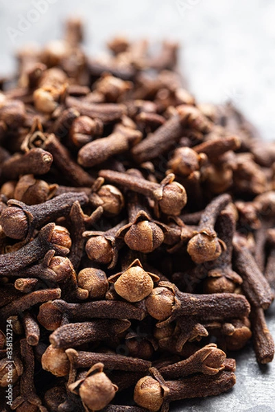 Fototapeta A close-up of dried cloves scattered on a textured light gray surface, Indian Indonesian spice.