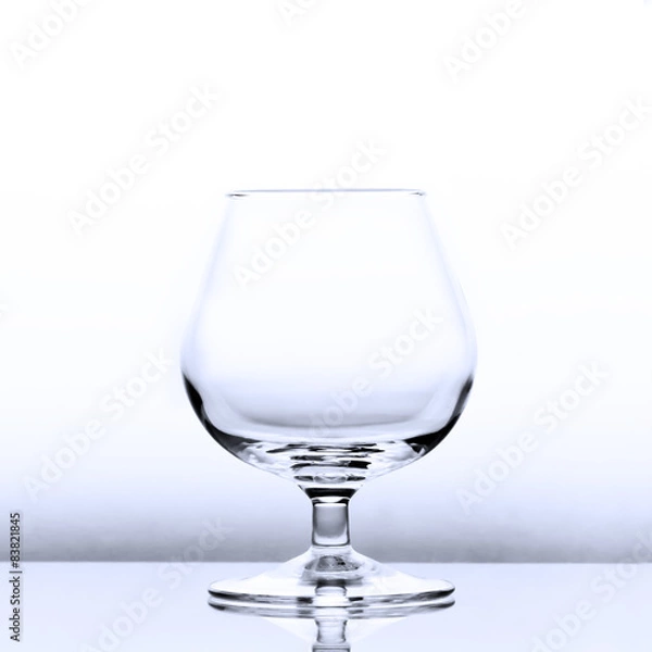 Fototapeta An empty cognac snifter in slightly blue light with a reflection