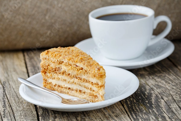 Fototapeta Tasty honey cake with cup of coffee on wooden background.