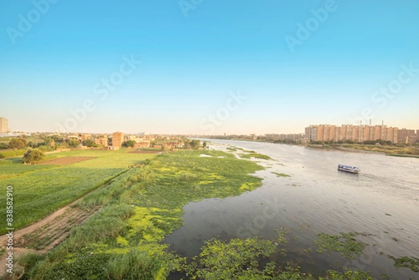 Fototapeta Nile River View, Cairo, Egypt, Buildings on the Right Bank and Green Fields on the Left Bank, Boat Sailing