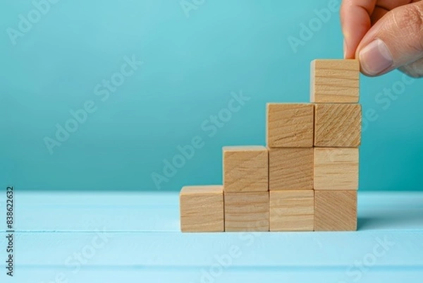 Fototapeta hand stacking wooden blocks in a geometric shape