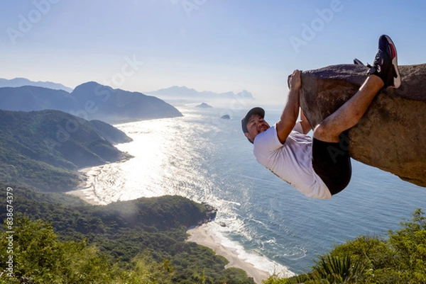 Obraz Adventurous climber hangs off Pedra do Telégrafo with breathtaking coastal view in Rio de Janeiro