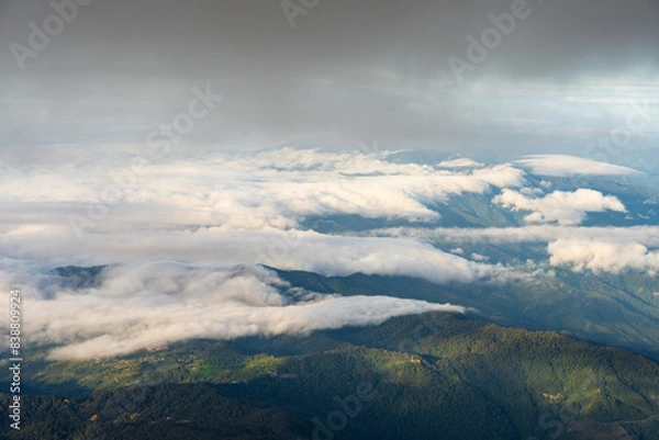 Fototapeta the clouds are floating over some mountains near a town and a forest