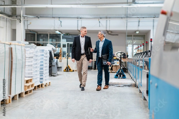 Fototapeta Two businessmen walking and talking in a factory
