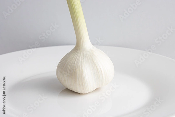 Fototapeta 白い皿の上に乗った、茎がついた一個の新ニンニク