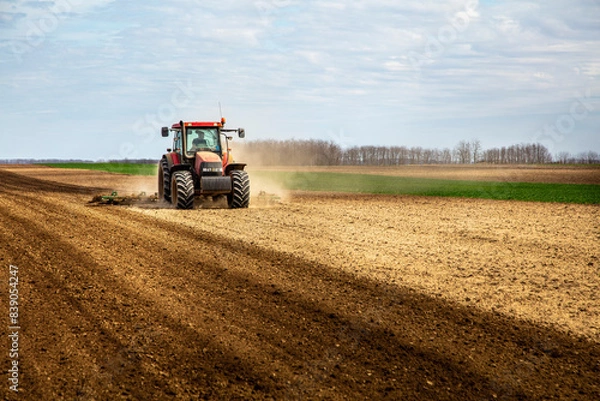 Fototapeta Farmer in tractor plowing field in spring