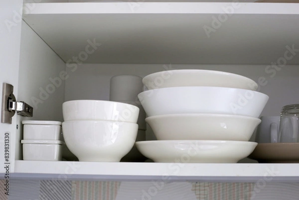 Fototapeta Clean dishes and tableware on a white shelf