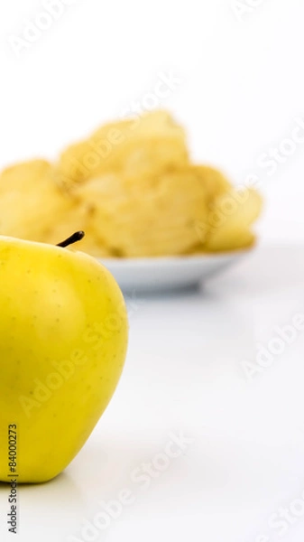 Fototapeta yellow apple vs yellow salty potato chips