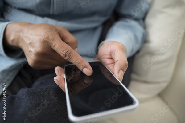 Fototapeta Men are using the latest smart phone sitting on the sofa