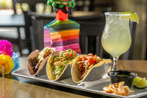 Fototapeta A Trio of Tasty Tacos - Suadero (braised brisket on blue corn tortilla), Grouper and Shrimp tacos with house-made salsa verde, grilled onion and lime, with a margarita.