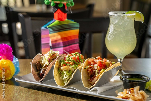 Fototapeta A Trio of Tasty Tacos - Suadero (braised brisket on blue corn tortilla), Grouper and Shrimp tacos with house-made salsa verde, grilled onion and lime, with a margarita.