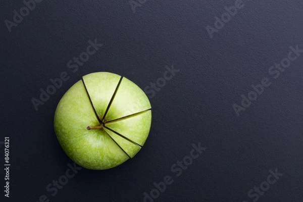 Fototapeta green apple cutting in the shape of pie chart on back board