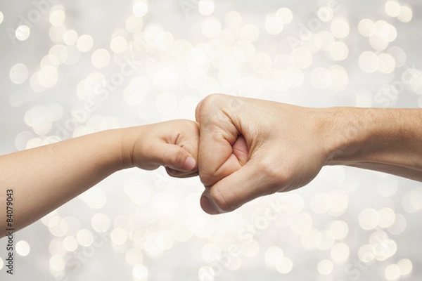 Fototapeta father and son punching fists on christmas lights background