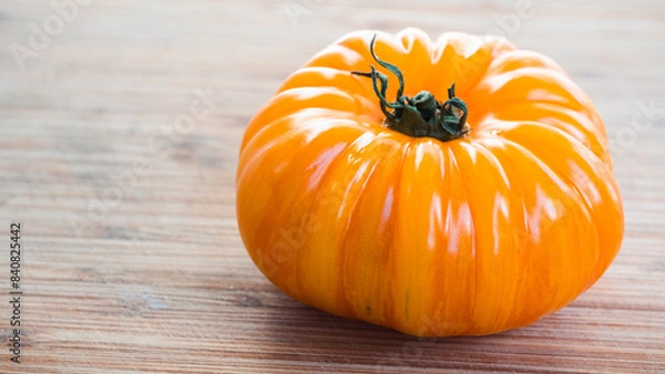 Fototapeta Bright orange colored gourmet  tomato sitting on the right side of the frame. Leaving the left side available for adding text.
Captured in a highly detailed close up. Harvesting season concept.