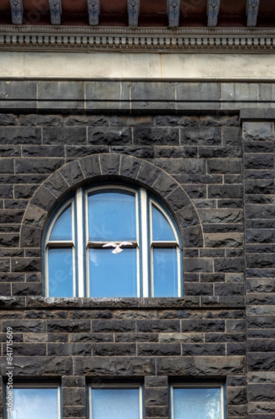 Fototapeta Arched Window in a Black and Brown Stone Block Building.