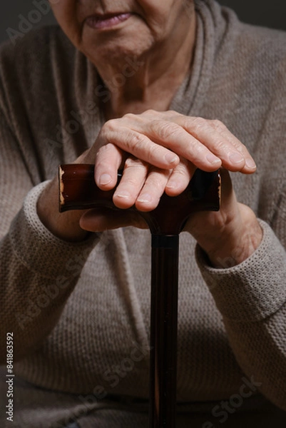 Obraz An elderly woman's hands on the handle of a cane. Hands of an elderly woman on a cane. Senior woman holding an old wood cane to support himself. Shallow depth of field