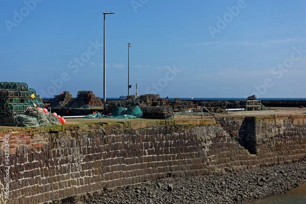 Obraz Hidden Stone steps to the Waters edge at low tide at Arbroath Harbour, with Fishing equipment and Pots scattered on the Quayside.