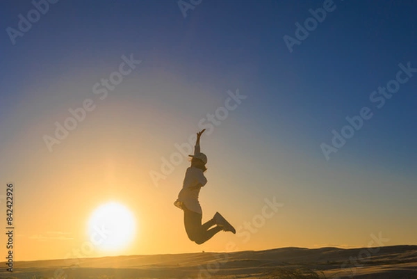 Fototapeta 夕暮れ、ジャンプする女のシルエット