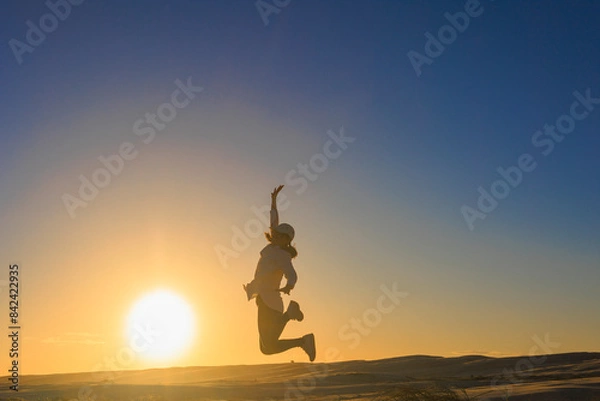 Fototapeta 夕暮れ、ジャンプする女のシルエット