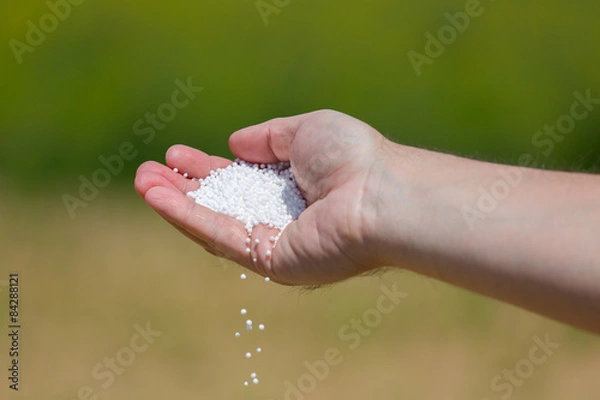 Fototapeta Hand full of small fertilizer