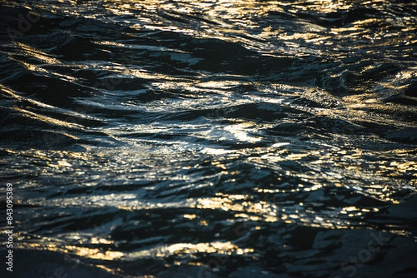Fototapeta Close up uf water surface during golden hour, creating an abstract pattern.