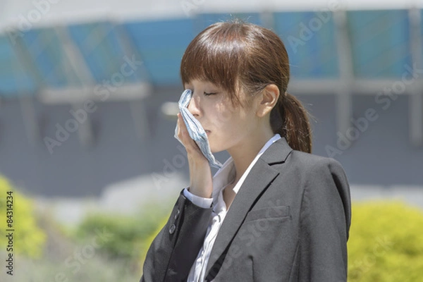 Obraz 休憩中の公園で汗を拭く若いビジネスウーマン