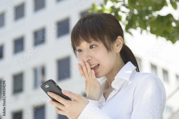 Obraz スマートフォンを見て喜ぶ若い日本人女性