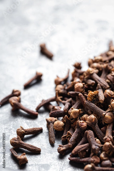 Fototapeta A close-up of dried cloves scattered on a textured gray surface, Indian Indonesian spice