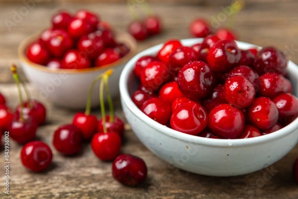 Fototapeta Cherries. Fresh ripe cherries with leaves on a textured wooden background. Fresh sweet organic cherry pile. Berries and fruits. Vegan. Healthy eating. Place for text. Copy space