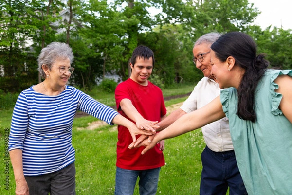Obraz A group of people place their hands in the center of a circle. The scene is cheerful and friendly, as the group seems to be enjoying each other's company.