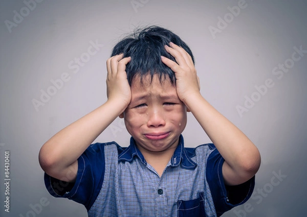 Obraz Asian boy crying over dark background