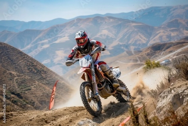 Fototapeta A motocross race in a rugged terrain with mountains in the background