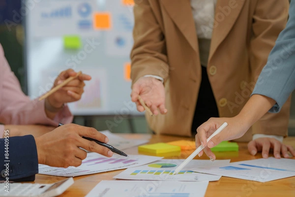 Fototapeta Close-up of diverse businesspeople gathering at the office desk to discuss company financial paperwork at a meeting together, multiracial colleagues brainstorm work with documents at an office.