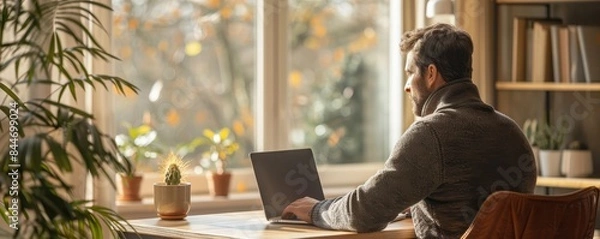 Obraz Man working from home, laptop on a minimalist desk, remote work efficiency, copy space for text.