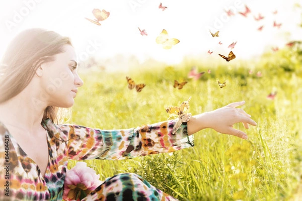 Fototapeta  Girl sitting in a meadow in a swarm of flitting butterflies.