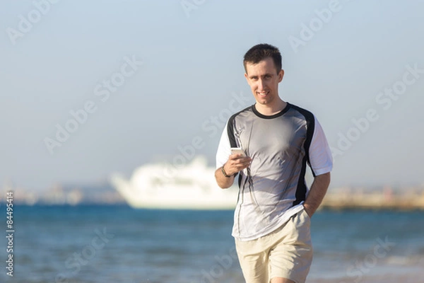 Fototapeta Young man using cellphone at sea