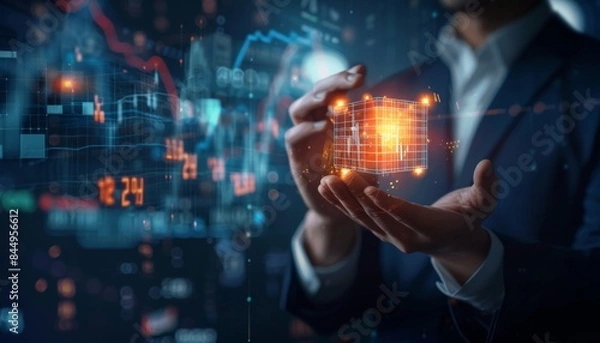 Fototapeta Illuminating Financial Success - Businessman Holding Glowing Energy Cube Surrounded by Data Charts on Dark Background
