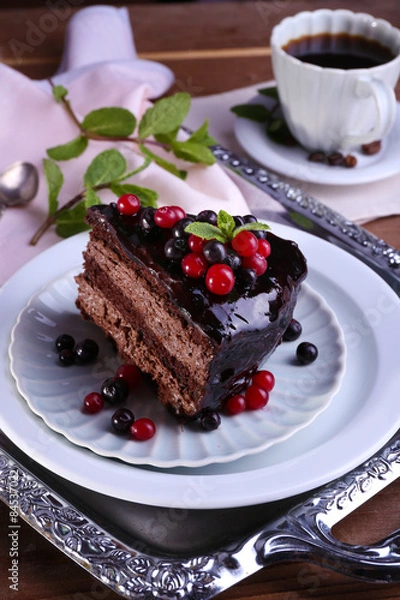 Fototapeta Delicious chocolate cake with berries and cup of coffee on table close up