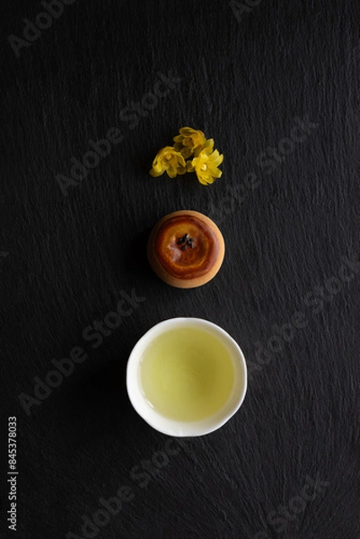 Fototapeta Japanese green tea, Wagashi, Ume (apricot) flowers and  in a beauty minimalist aesthetic arrangement on black granite board background. Japan.
