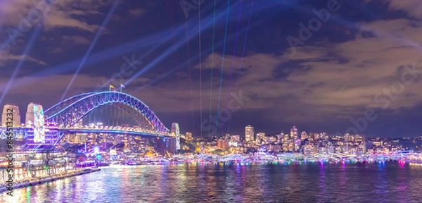 Fototapeta Colourful Light show at night on Sydney Harbour NSW Australia. The bridge illuminated with lasers and neon coloured lights  Vivid Sydney Laser and Light Drone show