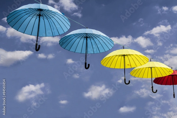 Fototapeta colored umbrellas hanging from a rope sky background